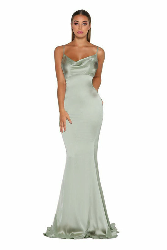 A slender figure stands confidently in a light green satin dress with a flowing silhouette. The setting is neutral, focusing attention on the dress and the model's posed expression.